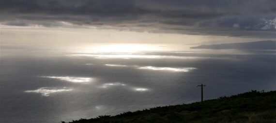 Die Sonne scheint an einzelnen Stellen durch die Wolken und verteilt Lichtflecken auf dem Meer.